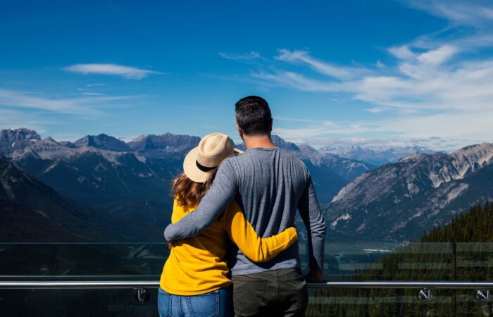 A couple embraces while enjoying a breathtaking view of the mountains in Banff, Alberta.
