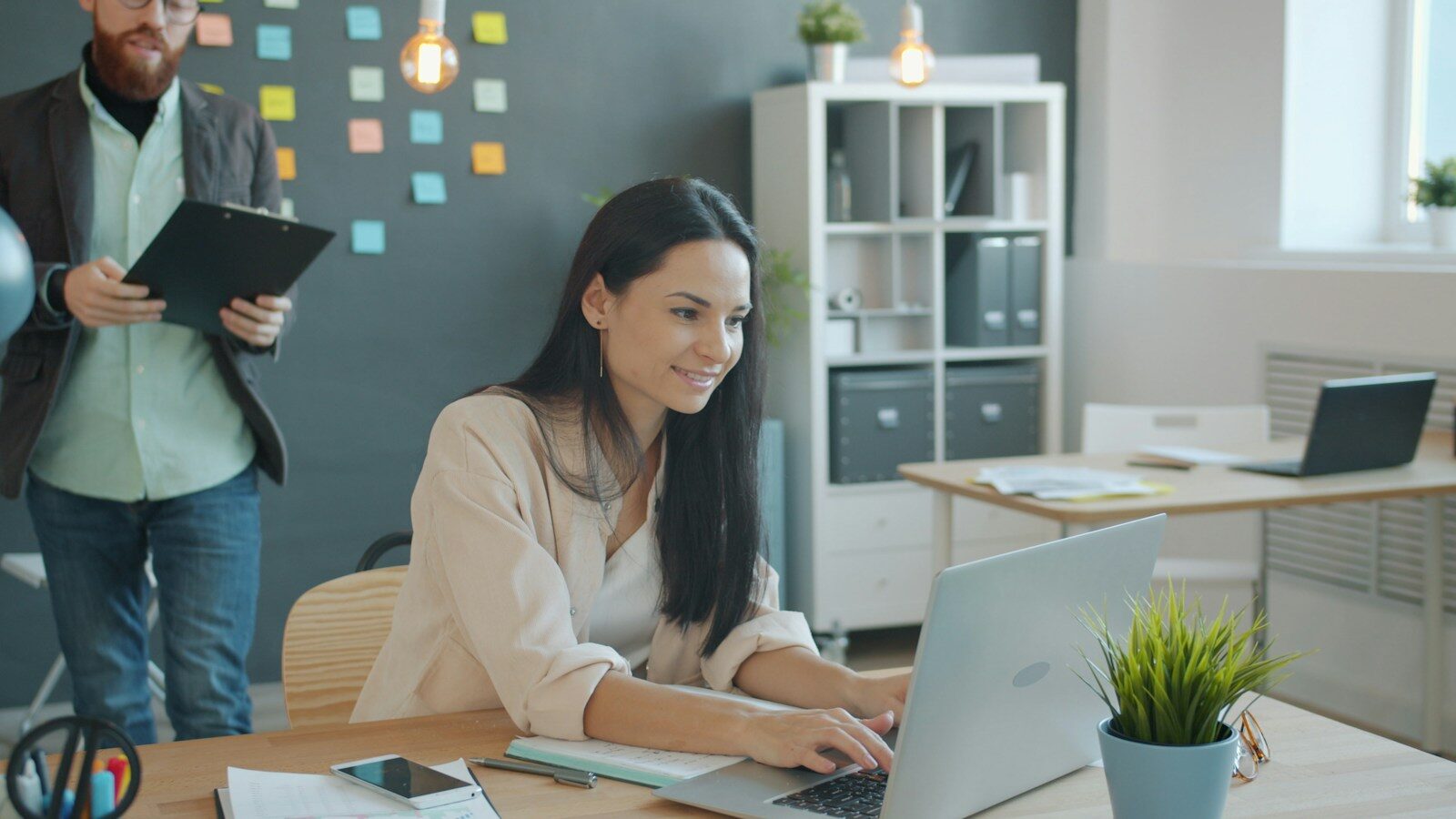 Woman working on laptop with man behind her